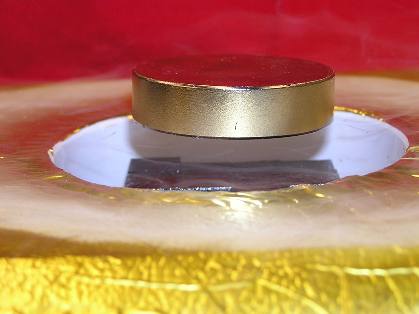 This image of a magnet levitated over a high-temperature superconductor array shows rectangular TFMs (black) levitating a heavy ferromagnet (silver) above a container of liquid nitrogen. 
