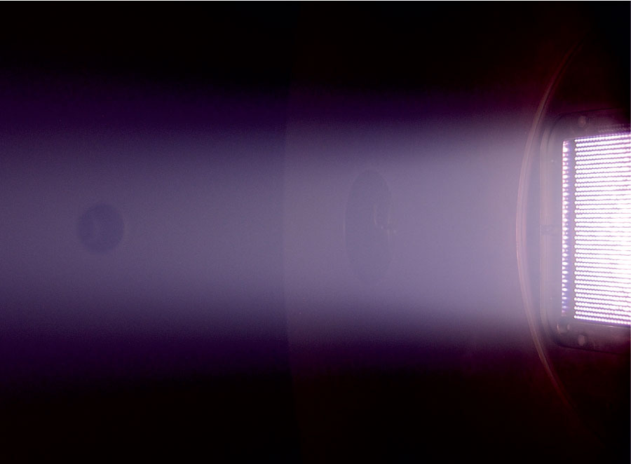 Image of the Neptune thruster (right) with plasma expanding into a space simulation chamber Credit: Dmytro Rafalskyi