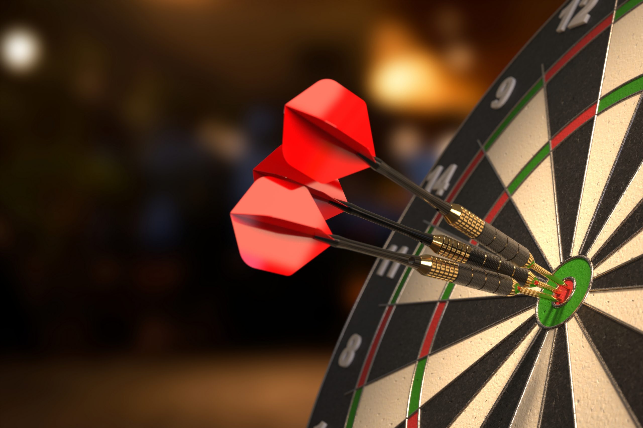 Three darts clustered in the center of a dartboard.