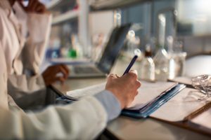 Researcher writing grant application notes in a laboratory