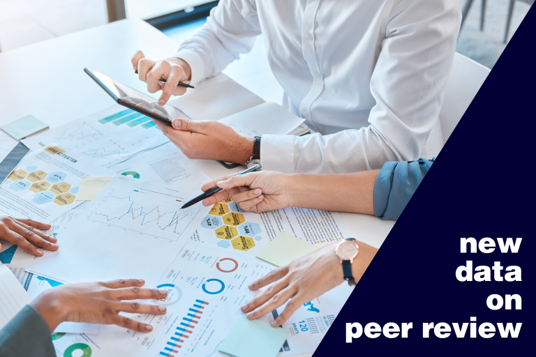 A group of peer reviewers discussing research data that is spread across a table.