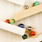 Marbles moving through a network of connected wooden tracks.