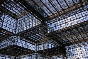 Steel framework and glass panels forming an interconnected structure with sunlight filtering through.