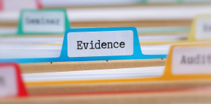 Close-up of a blue filing tab labeled "Evidence" surrounded by organized research files and colorful dividers.